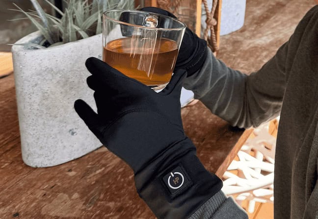 vrouw met verwarmde binnenhandschoenen met een kop thee in haar handen