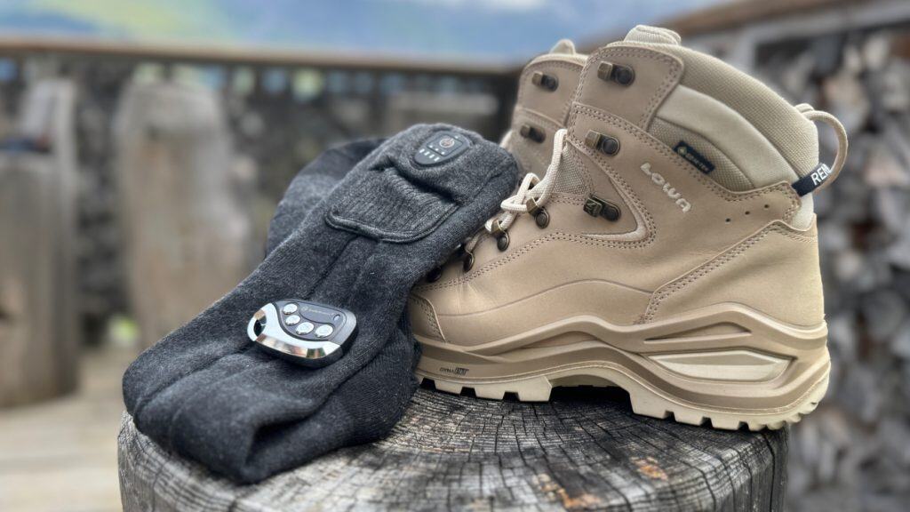 Verwarmde sokken op een boomstam, gelegen naast een paar wandelschoenen.