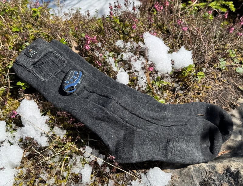 Verwarmde sokken met afstandsbediening van HeatPerformance® op gras met sneeuw, ideaal voor warme voeten tijdens koude dagen.