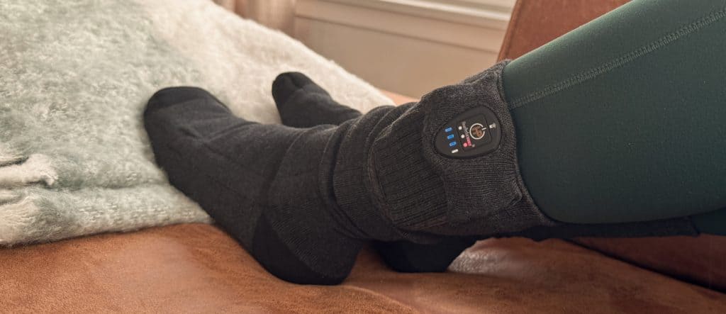 Vrouw ontspant thuis met verwarmde sokken van HeatPerformance®, comfortabel en energiezuinig.