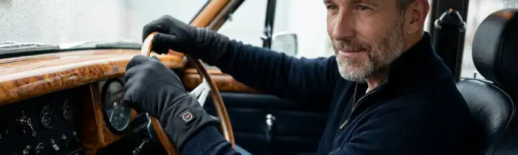 Man draagt verwarmde handschoenen in een auto.