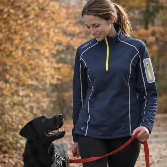 Vrouw met verwarmde pull-over aan het wandelen met de hond. In een bos in de herfst.